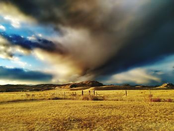 Scenic view of field against dramatic sky