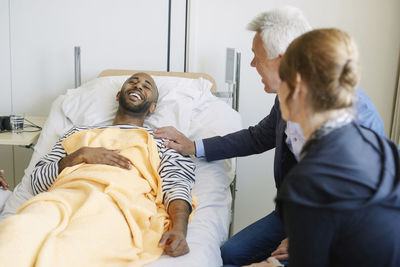 Father encouraging son while sitting by bed at hospital ward