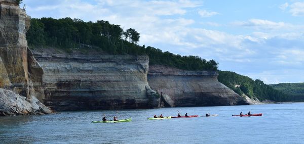 People kayaking on sea by rock formations