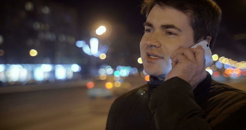 Portrait of young man looking away at night