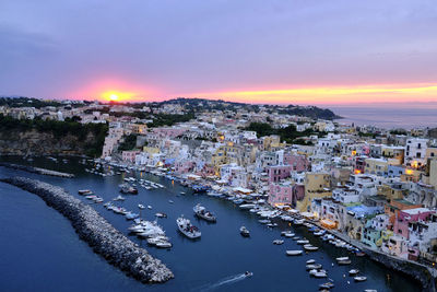 High angle view of river amidst buildings in town against sky at sunset