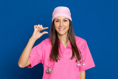 Portrait of smiling young woman against blue background