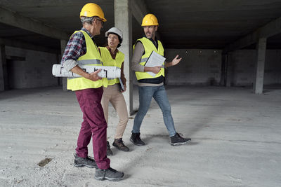 Full length of engineers walking at construction site