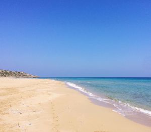 Scenic view of beach against clear blue sky