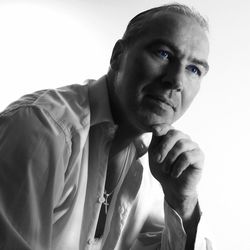 Thoughtful man with hand on chin looking away while sitting against white background