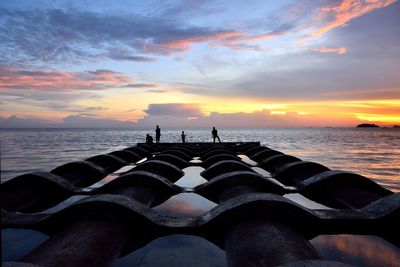 Low section of man on beach against sky during sunset