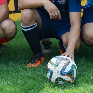 Low section of people playing soccer on field