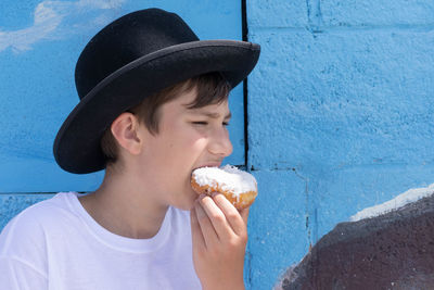 Portrait of girl eating ice cream against wall