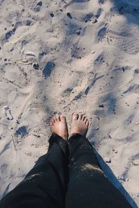 Low section of person standing on sand at beach