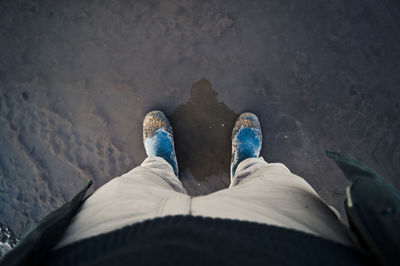 Low section of person standing on wet road