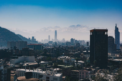 Cityscape by snowcapped mountains against clear sky