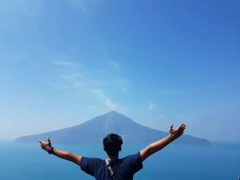 Low angle view of woman with arms raised against sky