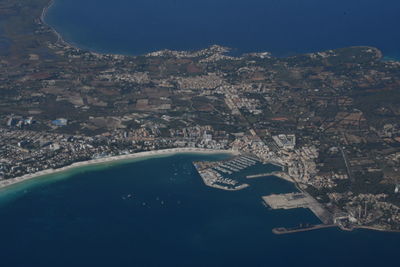 Aerial view of city by sea against sky