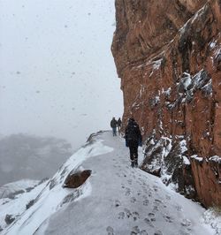 People walking on pathway at mountain during winter