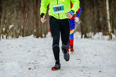 Low section of man walking on snow covered field