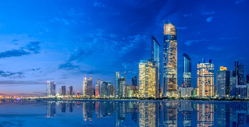 Illuminated buildings against blue sky at night