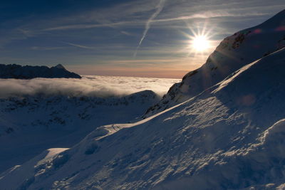 Scenic view of snow covered mountains against sky during sunset