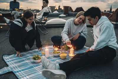 Male and female friends enjoying on building rooftop during sunset