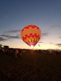 People and hot air balloon against sky during sunset