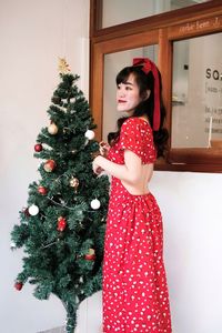 Young woman standing against christmas tree