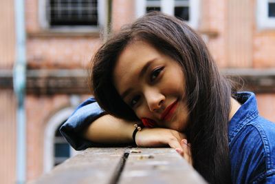 Portrait of smiling beautiful woman leaning on railing against building