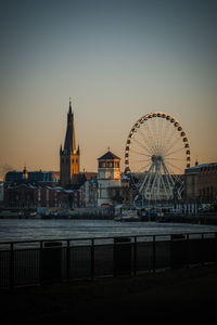 Ferris wheel in city against clear sky at dusk