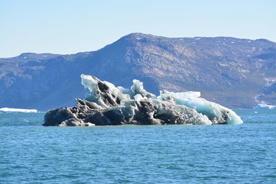 Scenic view of sea and mountains against clear blue sky