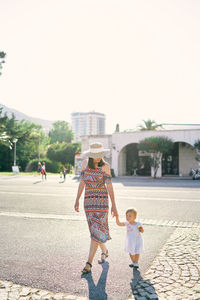 Full length of women walking in city against sky