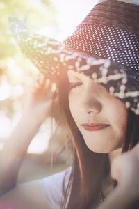 Close-up of smiling young woman wearing hat during sunny day