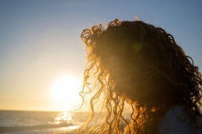 Woman at beach against sky during sunset