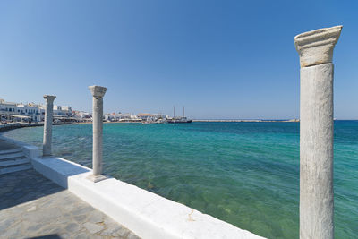 Scenic view of footpath by sea against clear blue sky