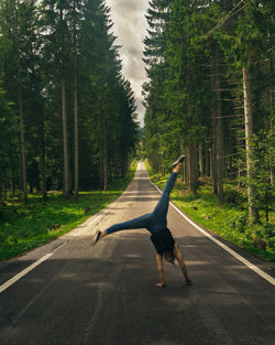 Woman doing handstand on road in forest