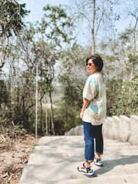 Full length of boy standing on footpath by road