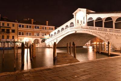 Arch bridge over canal in city at night