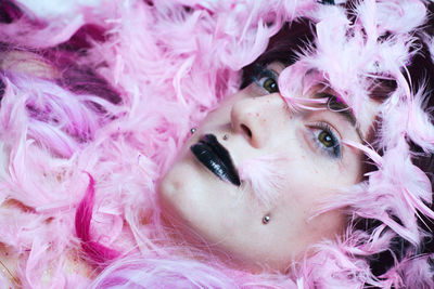 Close-up of woman with make-up amidst pink feathers