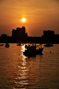 Silhouette boat in sea against orange sky