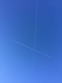 Low angle view of vapor trails in blue sky