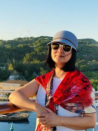 Portrait of young woman in sunglasses against sky