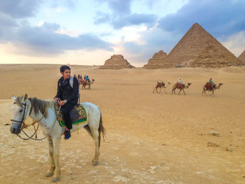 Group of people riding horse on desert