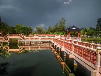 Bridge over river by buildings against sky