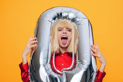 Smiling young woman with stuffed toy against yellow background