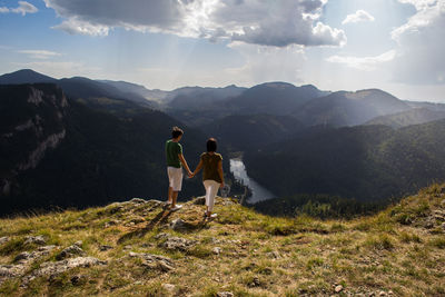 Scenic view of mountains against sky with two people holding hands