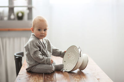 Funny kid in a comfortable sweater playing in a cozy real kitchen, lifestyle and light smoky toning