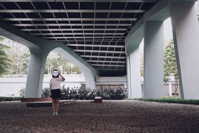 Woman holding mirror while standing below bridge