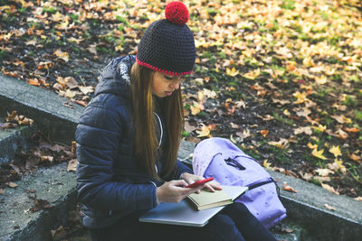 Girl sitting in the park using smartphone. teen using mobile phone, chat with friends and classmates