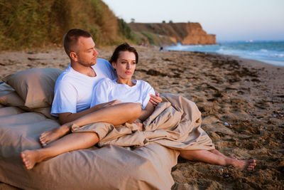 Young couple wrapped in a blanket outdoors.