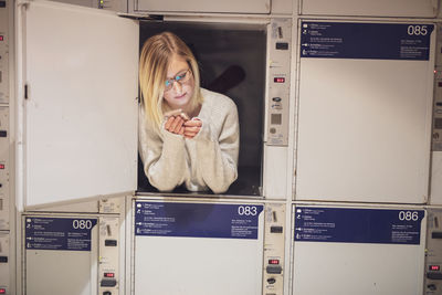 Young woman using phone in locker