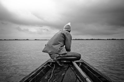 Rear view of man on boat in sea against sky