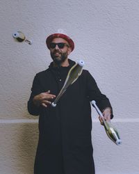 Young man wearing sunglasses standing against wall