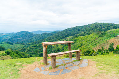 Rear view of woman sitting on bench against mountain